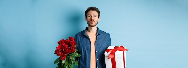 Free photo love and valentines day concept romantic boyfriend pucker lips for kiss bring bouquet of red roses a