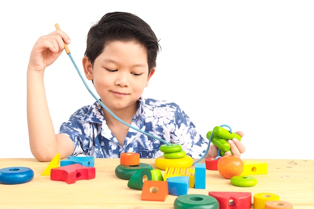 素敵なアジアの少年はカラフルな木のブロックのおもちゃで遊ぶ
