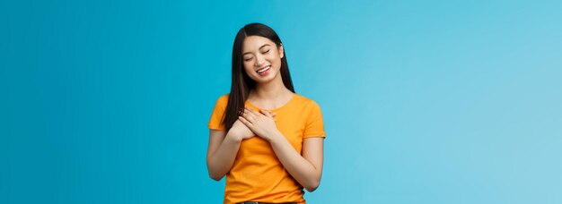 Lovely asian woman with dark haircut close eyes press hands heart gently smiling tilt head cute cher