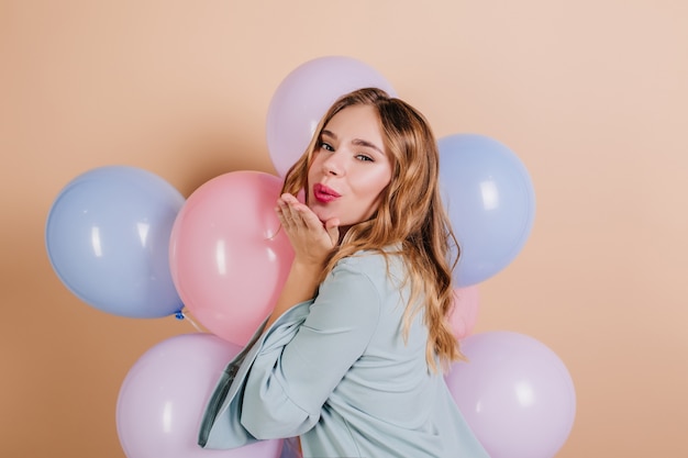 Lovely birthday woman with wavy hair posing on light wall