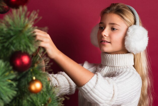 Lovely blonde girl decorating tree