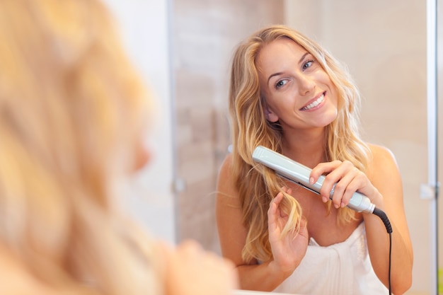 Foto gratuita belle donne bionde che arricciano i capelli dalla piastra