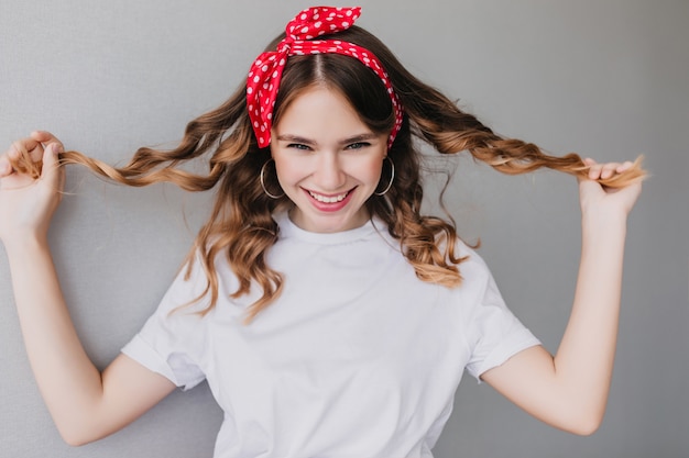 Foto gratuita bella ragazza caucasica che gioca con i suoi capelli ondulati e sorridente. meravigliosa giovane donna bianca che esprime felicità.