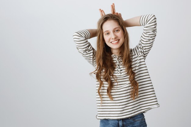 Lovely cheerful girl showing bunny ears gesture and smiling cute