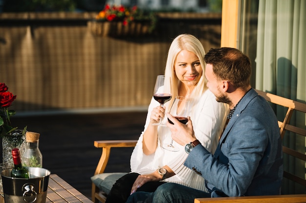 Free photo lovely couple holding red wine glasses looking at each other