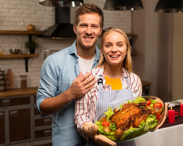 Lovely couple looking at the camera and holding the thanksgiving turkey