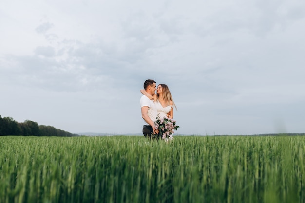 The lovely couple in love embracing and keeping bouquet