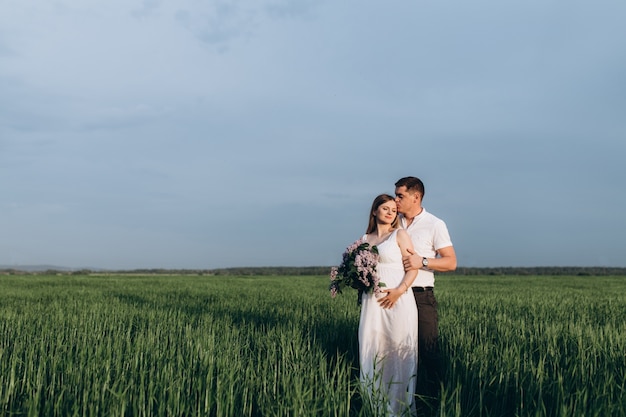 The lovely couple in love embracing and keeping bouquet