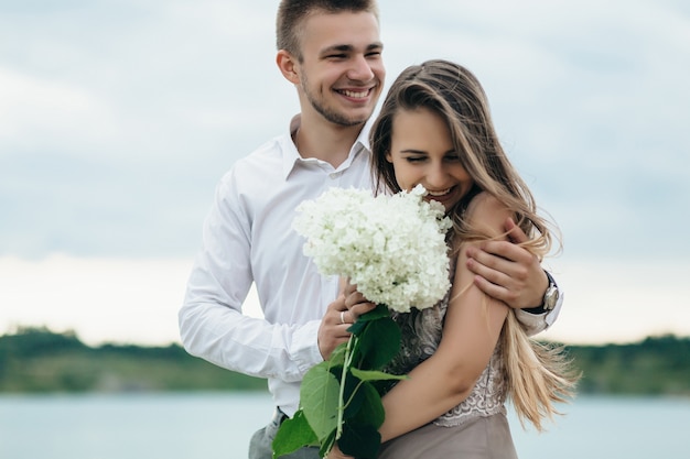 The lovely couple in love embracing near river