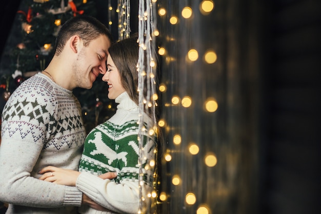 The lovely couple in love embracing near wall