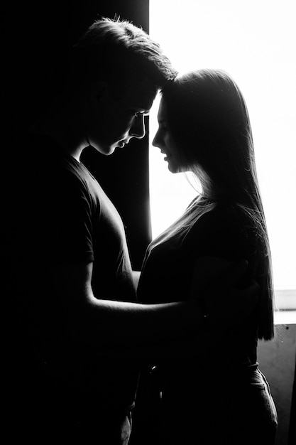 The lovely couple in love embracing near window