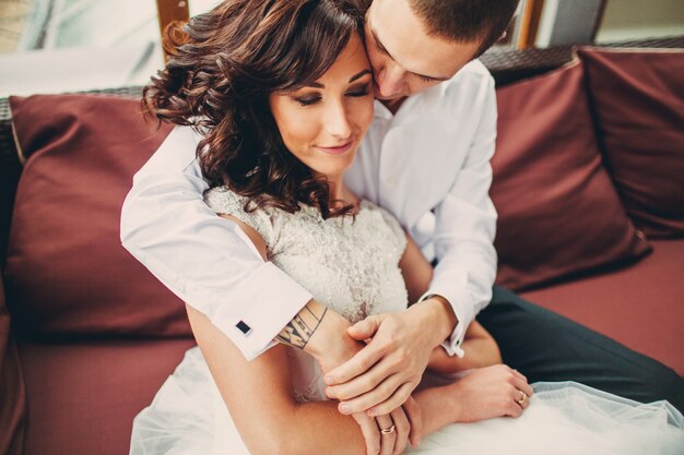 The lovely couple in love embracing on the sofa