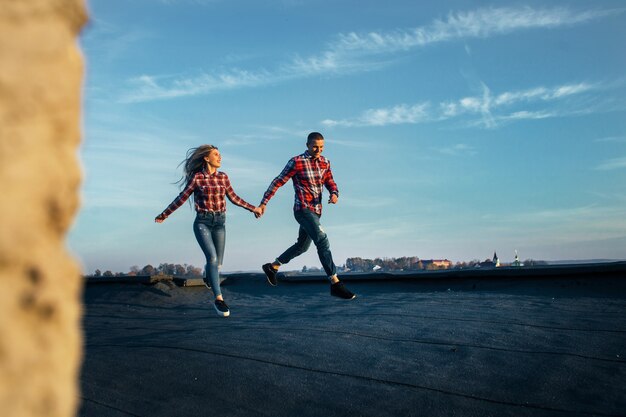 The lovely couple in love running along the roof