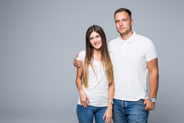 灰色の背景で隔離の笑顔の白いTシャツの素敵なカップルの男と女