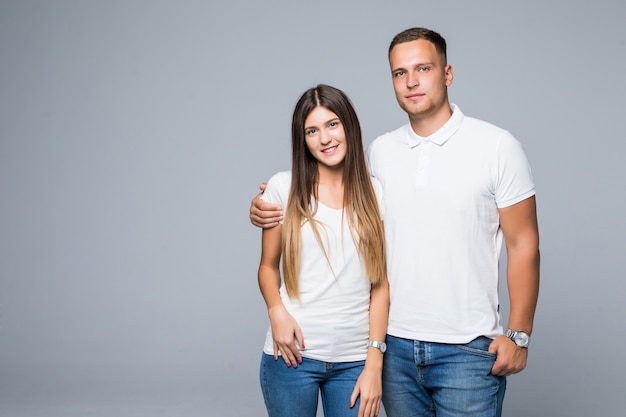 Lovely couple man and girl in white tshirts smiling isolated on grey background