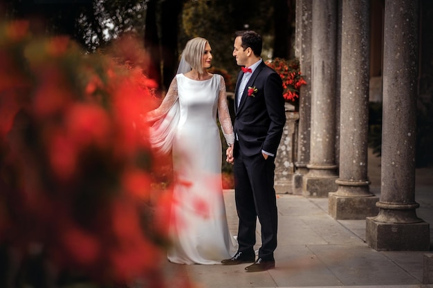 Lovely couple of newlyweds - bride and groom walking around the old beautiful stone palace outdoors.
