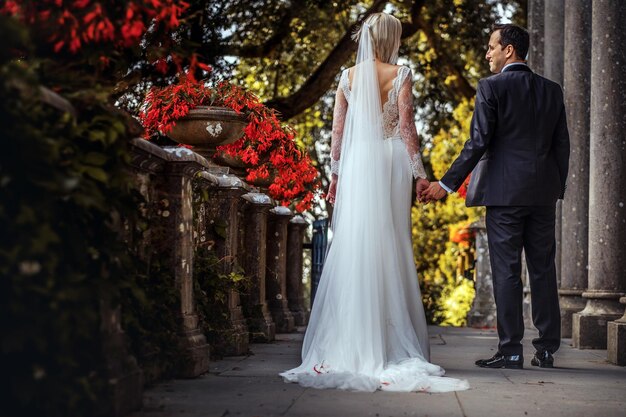 Lovely couple of newlyweds - bride and groom walking around the old beautiful stone palace outdoors.