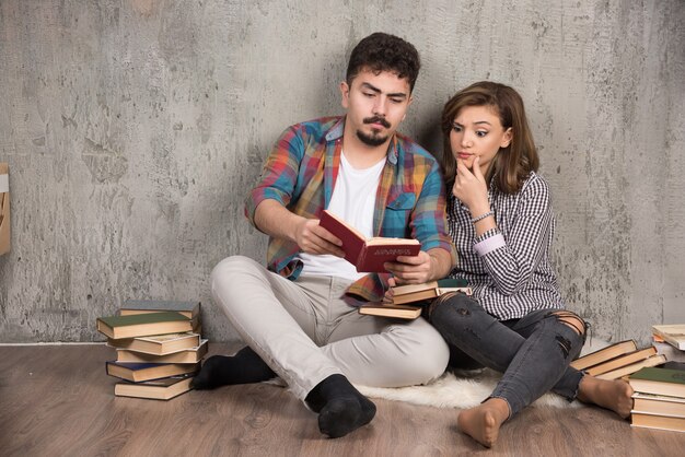 바닥에 앉아있는 동안 재미있는 책을 읽고 사랑스러운 커플