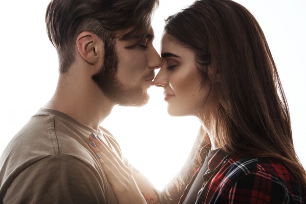 Lovely couple. Side view of man kissing girlfriend to nose.