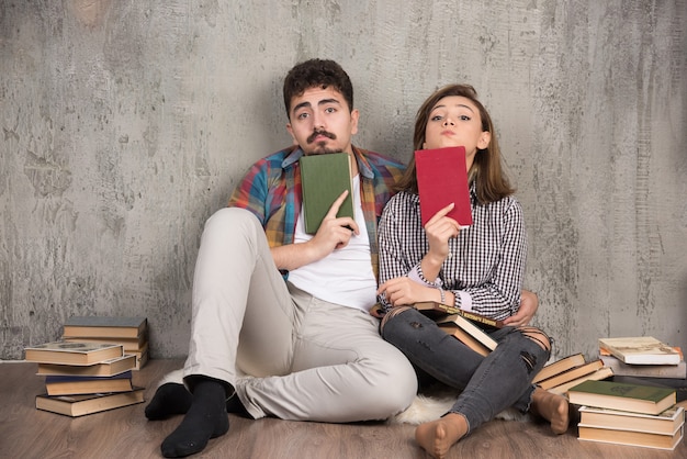 Free photo lovely couple sitting on floor and holding books