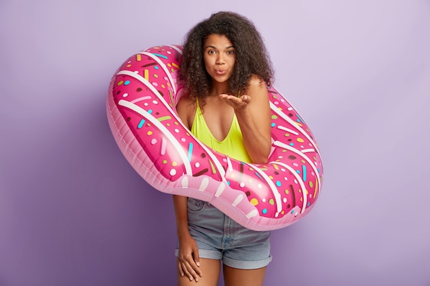 Lovely curly haired dark skinned young woman wears stylish summer outfit