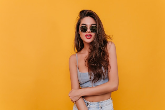 Lovely dark-haired woman in trendy sunglasses playfully posing 