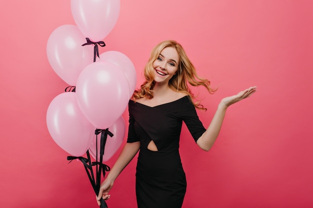 Прекрасная европейская девушка наслаждается фотосессией с розовыми воздушными шарами. Изумительная изящная девушка-модель танцует в свой день рождения.
