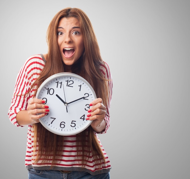 Lovely female holding round clock in hands. 