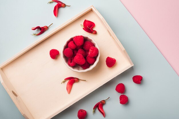 Lovely flowers concept with wooden tray and red fruits