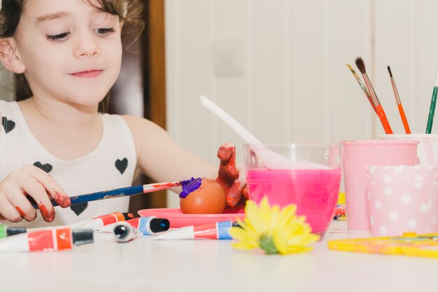 Lovely girl painting egg with violet