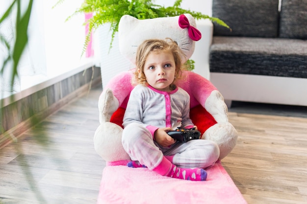 Lovely girl playing video game in armchair