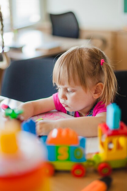 Lovely girl sitting at table in playroom