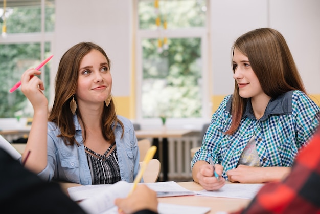 Lovely girls with classmates at desk