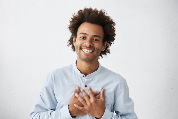 Uomo afroamericano di buon carattere adorabile in camicia bianca con un sorriso affascinante e un'espressione amichevole