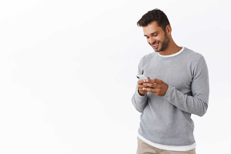無料Photo 素敵な格好良い男がスマートフォンのアルバムをスクロールして素敵な思い出を思い出してください冬の休暇中に携帯電話で撮った写真を見て笑顔でチャットしている友達はトラッカーアプリケーションを使用するか、オンラインで買い物をする
