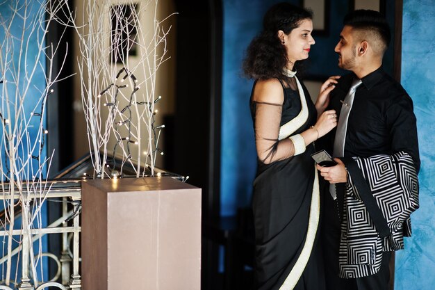 サリーで恋をしている素敵なインドのカップルとレストランでポーズをとったエレガントなスーツ
