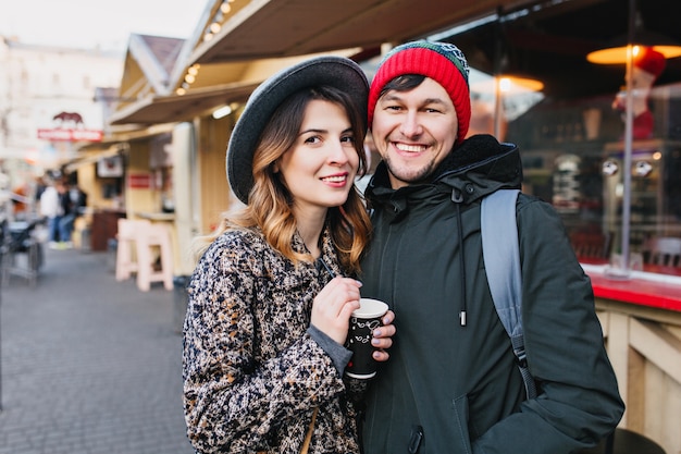 Bella coppia gioiosa agghiacciante, abbracciando sulla strada nel periodo natalizio. vere emozioni d'amore, divertirsi, godersi lo stare insieme, appuntamenti, relazioni romantiche, felicità insieme.