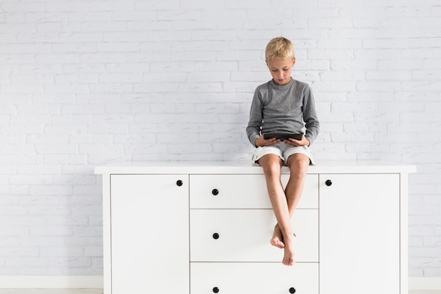 Free photo lovely little boy having fun with tablet