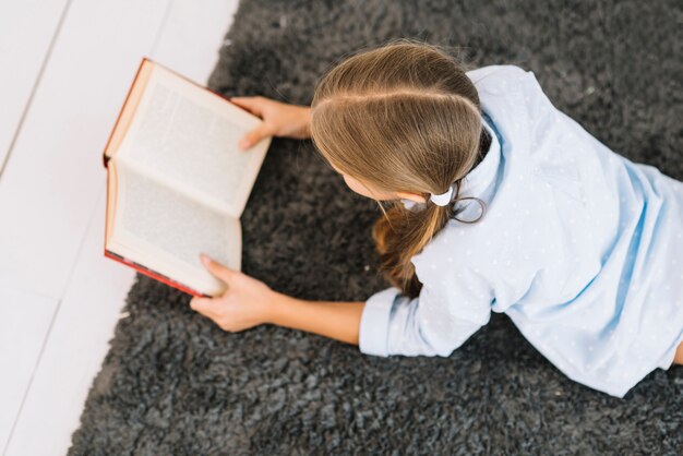Милая маленькая девочка читает книгу