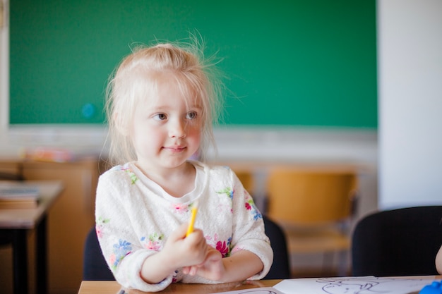 Lovely little girl sitting in classroom