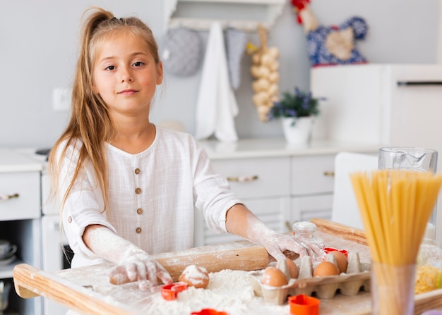 Bambina adorabile che usando il rullo della cucina