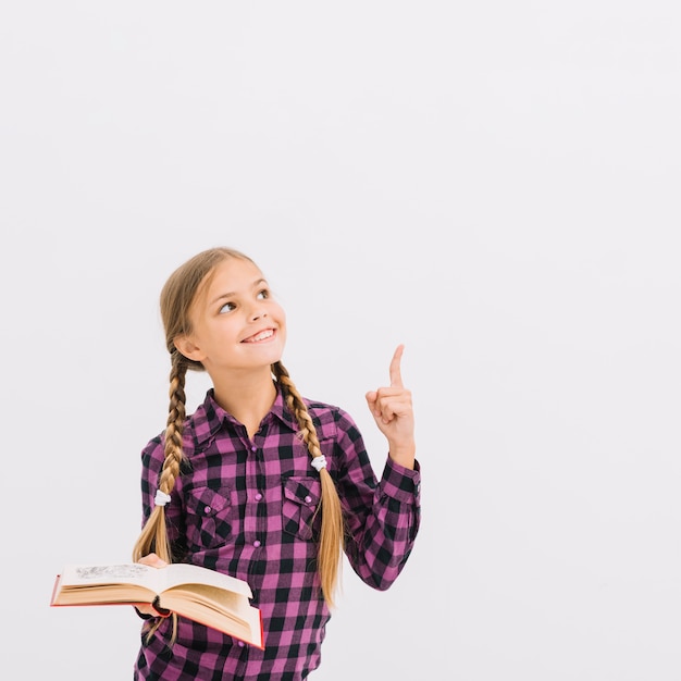 Bambina adorabile con un libro che indica in su