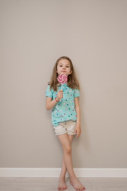 Lovely little girl with lollypops on beige background