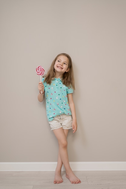 Free photo lovely little girl with lollypops on beige background