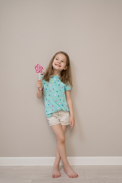 Lovely little girl with lollypops on beige background