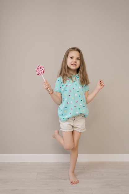 Lovely little girl with lollypops on beige background