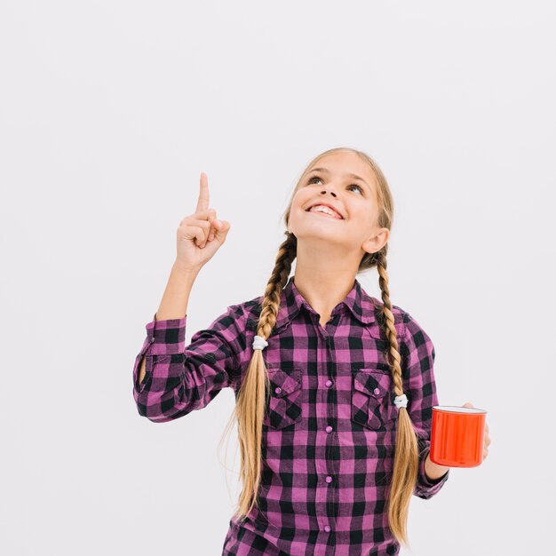 Lovely little girl with a mug pointing up