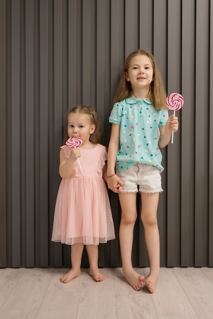 Free photo lovely little girls with lollypop on gray background