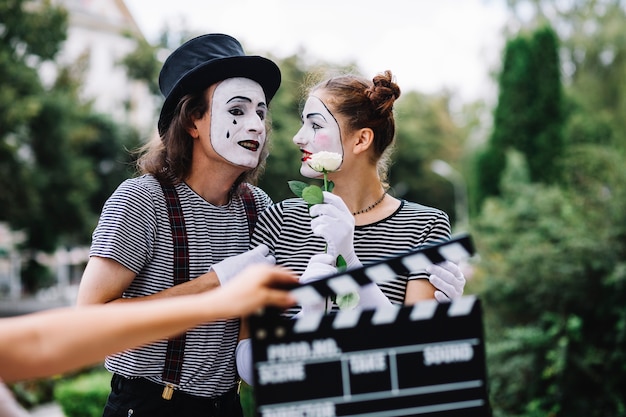 Free photo lovely mime couple with flower standing in park