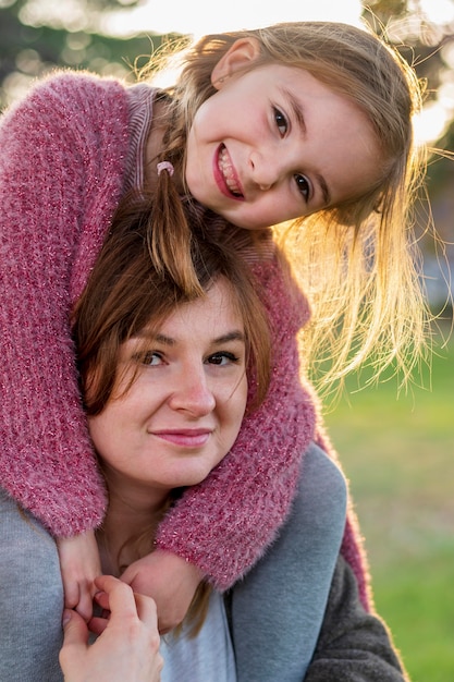 Free photo lovely mother carrying daughter on shoulders